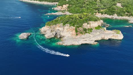 una lancha rápida atravesando aguas azules cerca de los exuberantes acantilados de la isla de corfú, vista aérea