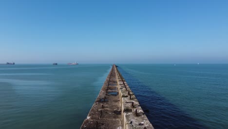 fly over shot over a harbour, port wall, view over a ship leaving or entering the port