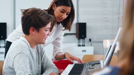 Männlicher-Schüler-Mit-Lehrer,-Der-Im-Musikunterricht-Klavier-Spielt