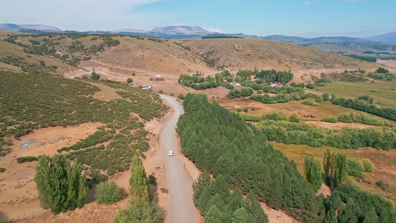 Ripresa aerea in carrello di un'auto che guida su strada sterrata attraverso una valle arida. Liucura, Lonquimay, Cile
