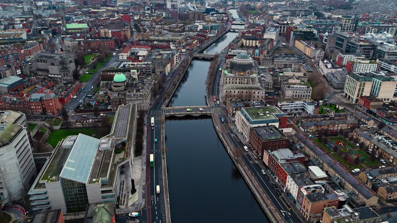 Luftaufnahme mit einer Drohne der irischen Hauptstadt Dublin mit belebten Straßen voller Verkehr und TouristInnen, die bei Sonnenaufgang im Winter durch die leuchtenden Straßen mit irischer Architektur laufen