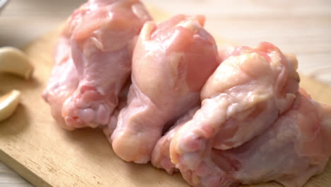 Alas de pollo crudo fresco sobre tabla de madera con ingredientes