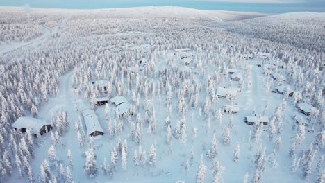 aerial surround of snowy forest landscape and cabins in lapland, finland, arctic circle