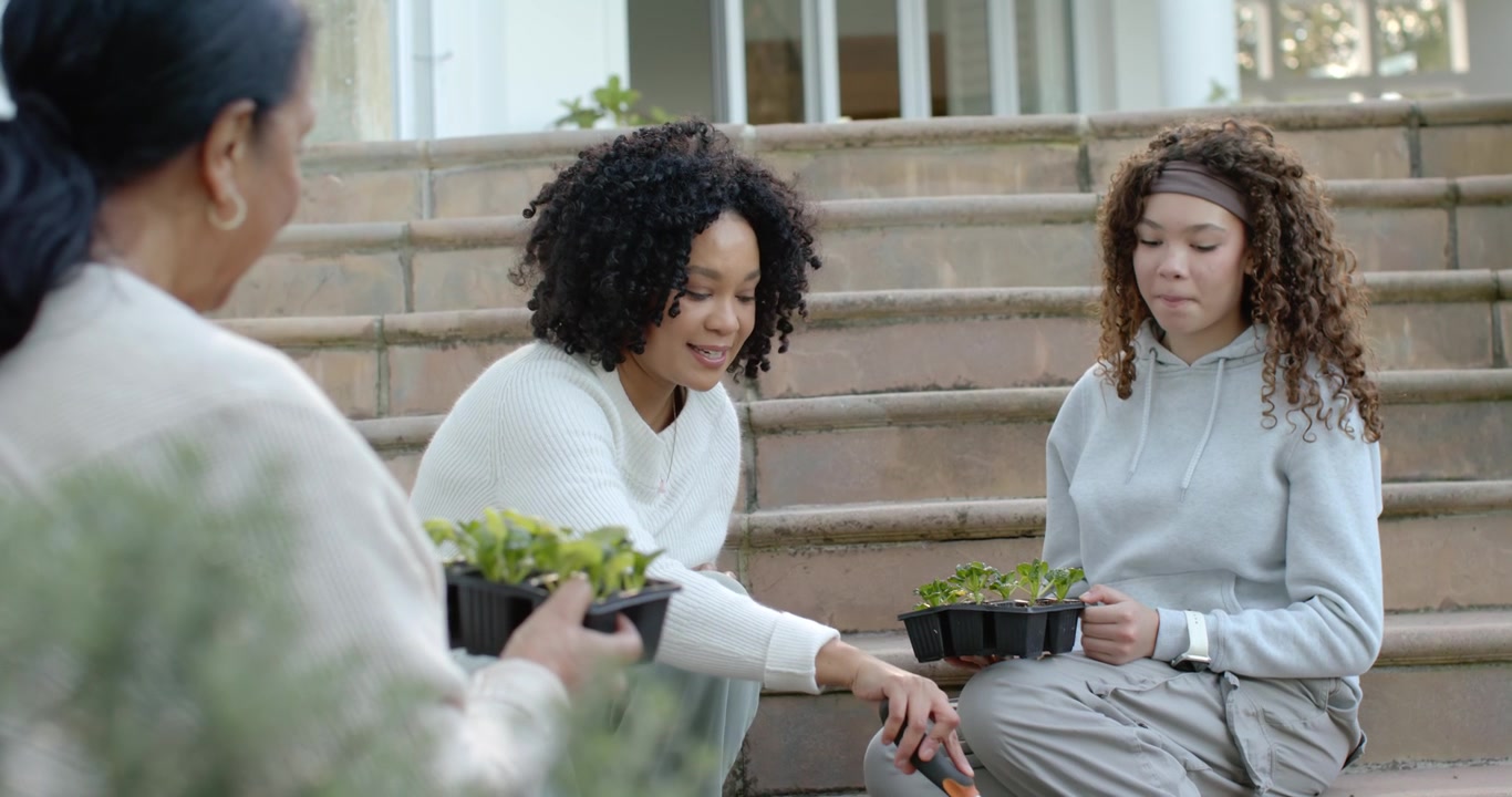 African American female family sitting on steps, Senior passing tray, Adult planting with trowel