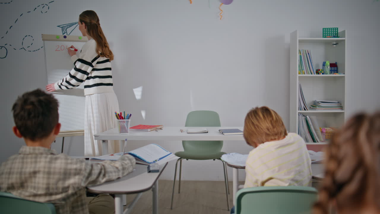 Elementary school teacher writing board at class room. Children studying lesson