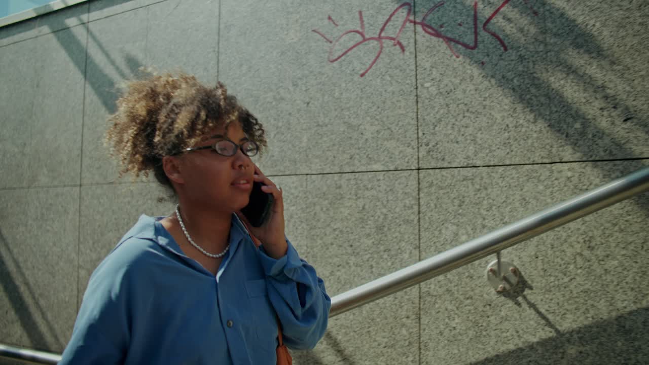 Donna al telefono sale le scale con un caffè