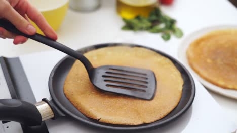 anonymous person flipping a pancake in the frying pan