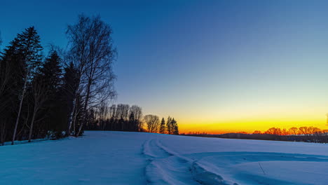 sun setting down with vibrant bright colors behind snowy rural landscape, fusion time lapse