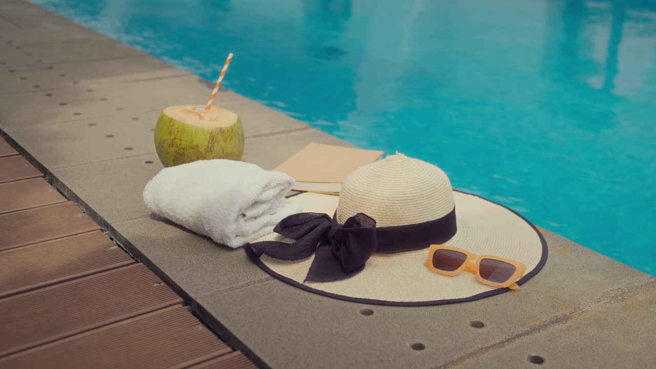 Kokosnussdrink, Sonnenhut und Handtuch für einen tropischen Urlaub am Pool
