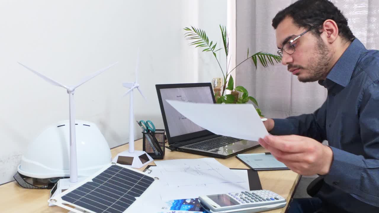 Ingeniero mecánico finalizando un diseño de turbina eólica en un portátil