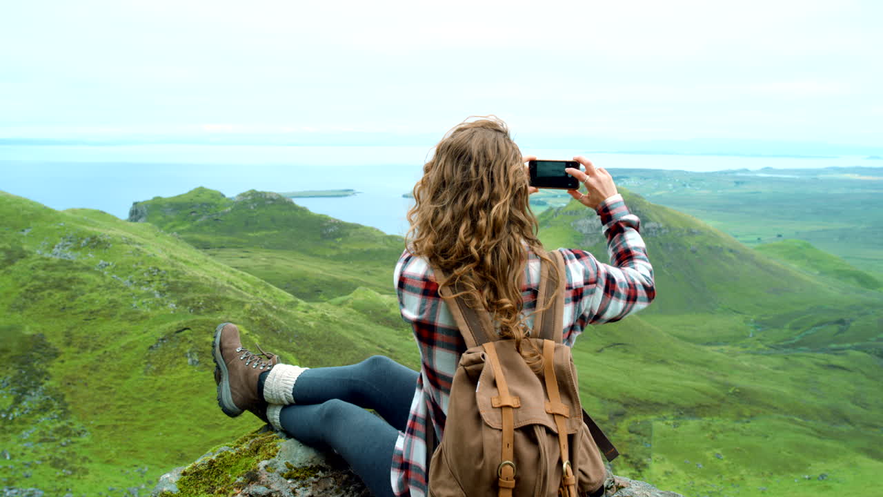 mujer tomando una foto de una vista panorámica desde la cima de una montaña