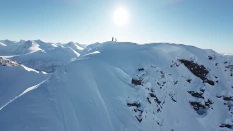 skiier on snowy mountain ridge top, fpv drone view
