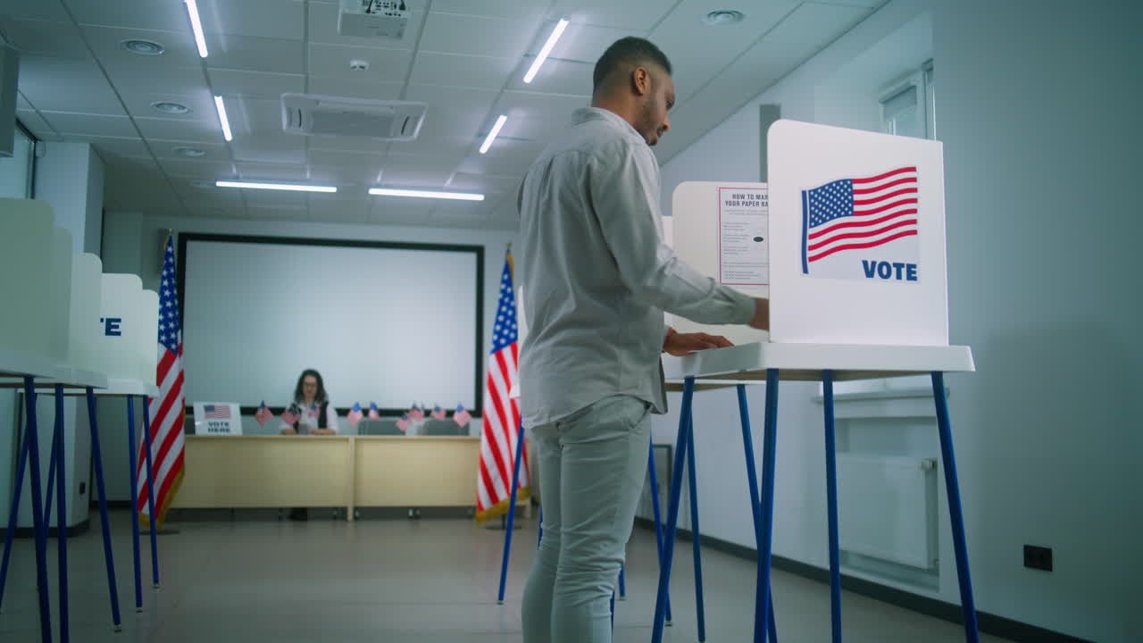African American Man Takes Paper Ballot and Walks to Voting Booth African American Man Takes Paper Ballot from Female Polling Officer at Polling Station and Walks to Voting Booth National Election Day in the United States of America Civic Duty and Democracy