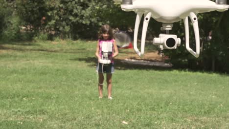 una niña pequeña volando un dron jugando al aire libre en verano en el campo de hierba verde piloto remoto en cámara lenta