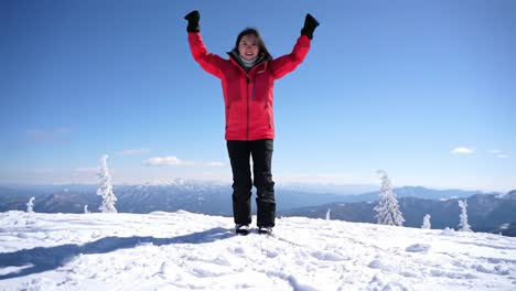 a joyful moment on a snow-capped mountain: celebrating the beauty of nature with a bright smile and outstretched arms in stunning winter landscape
