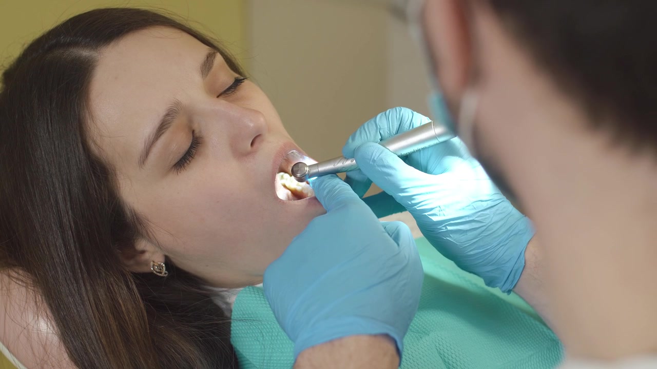 Dentist Performing Dental Procedure on Young Woman in Clinic