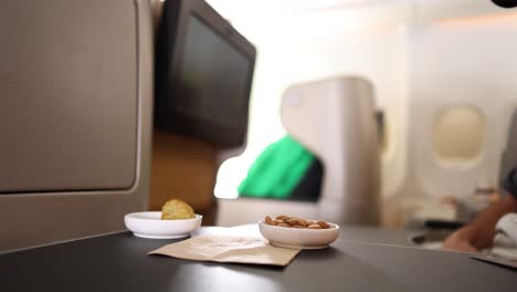 un pasajero alcanzando un bocadillo en la bandeja del avión