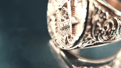 a macro detailed tilt up shot of a golden textured freemasons ring, on a rotating stand, mirror reflection, illuminati symbol, professional studio lighting, 4k video