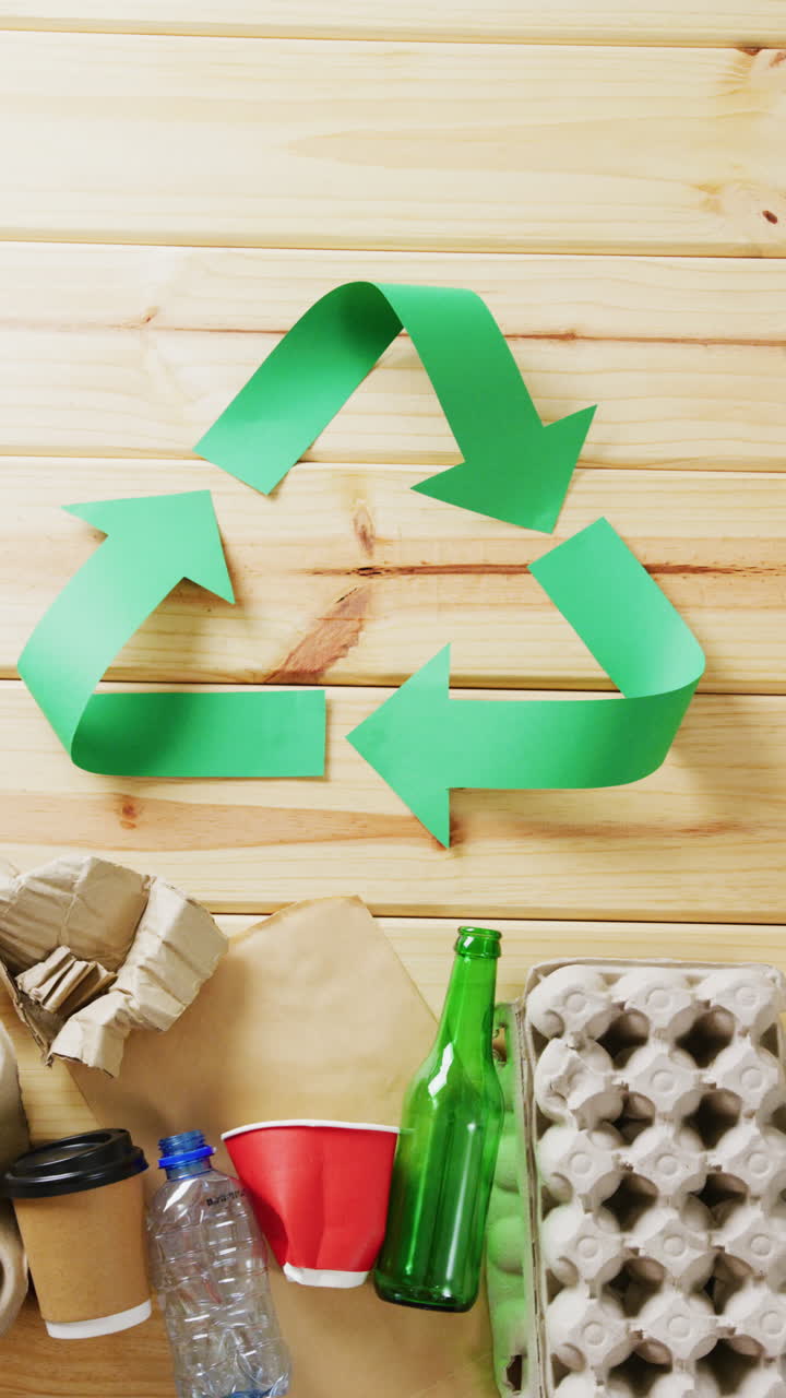 Vertical video of trash and recycling symbol of green arrows with copy space on wooden background