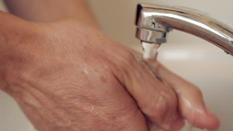 Caucasian-male-washing-hands-in-a-white-basin