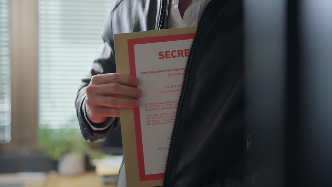 Man unzips leather jacket, discreetly pulling out a secret folder. Secrecy, espionage, covert operations, or confidential dealings. Classified information, crime, business, or intelligence operations.