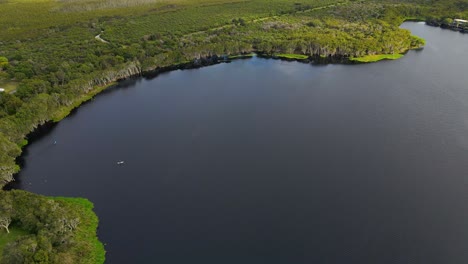 Paddleboarding-On-The-Tranquil-Water-Of-Lake-Ainsworth---Lennox-Head,-NSW