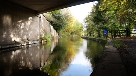 under old canal bridge waterway sunny autumn reflections on water with rainfall drizzle