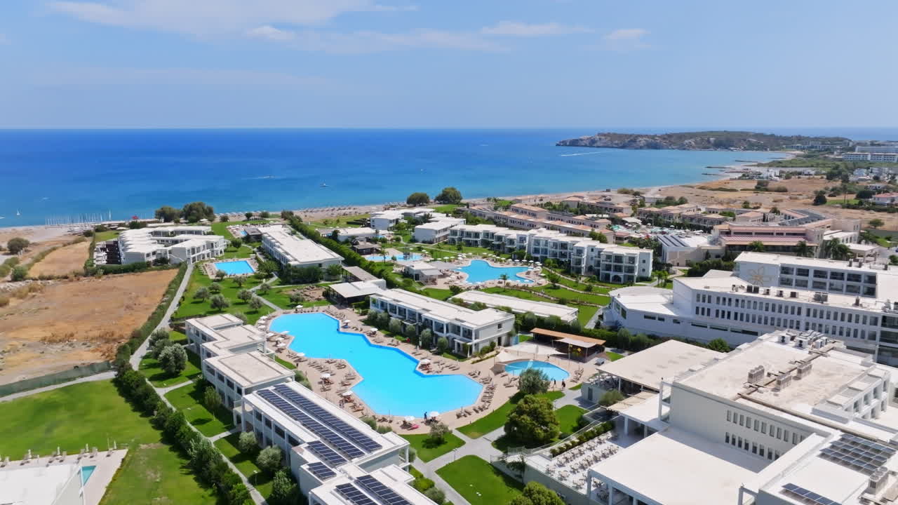 Drone flying over hotel and pools, sunny day on the coastline of Rhodes, Greece