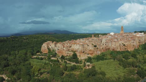 Drohnenaufnahmen-Der-Historischen-Mittelalterlichen-Stadt-Pitigliano,-Ein-Meisterwerk-Mittelalterlicher-Architektur-Auf-Einem-Natürlichen-Felsen-In-Der-Idyllischen-Landschaft-Der-Toskana,-Italien-Mit-Grünen-Bäumen-Und-Blauen-Hügeln