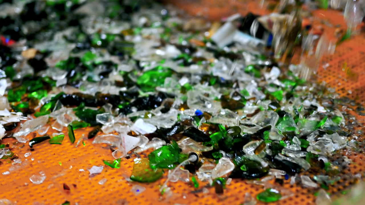 Process of sorting glass garbage on a vibrating conveyor belt at waste sorting plant. Slow motion