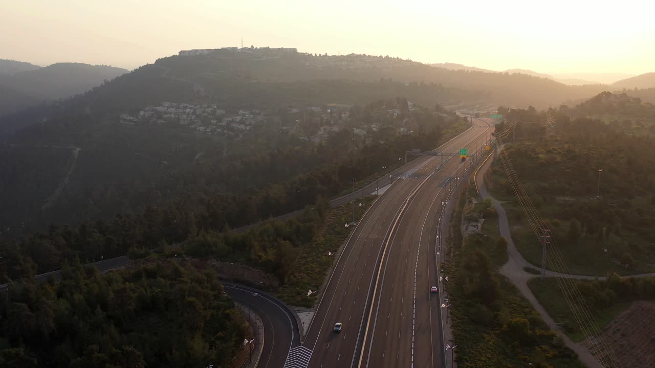 Aerial View of a Highway Winding Through Forested Hills at Sunset