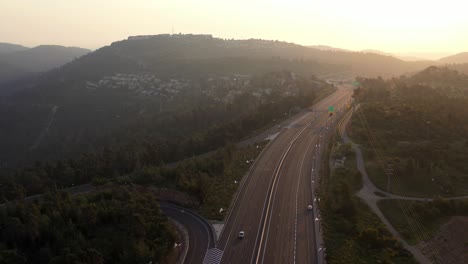 aerial view of a highway winding through forested hills at sunset