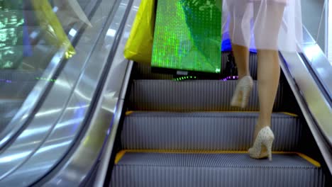 women walking up escalator in shopping mall