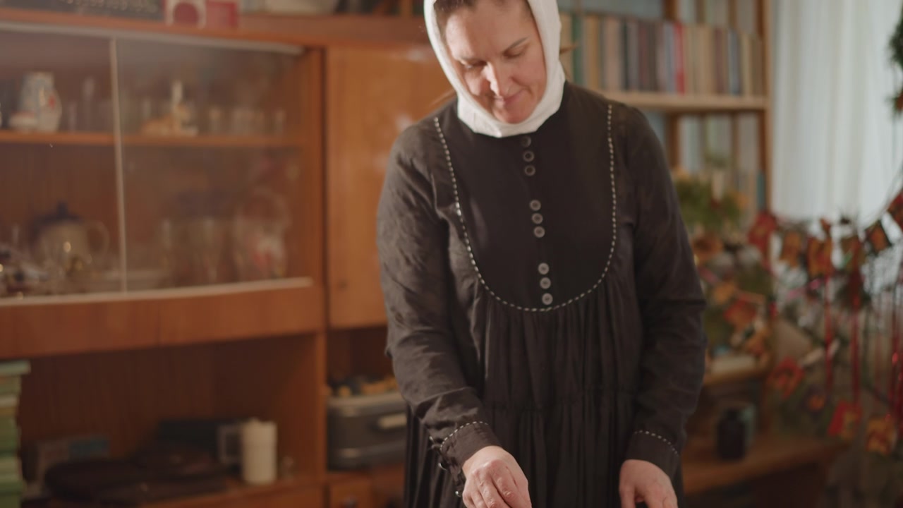Hvit eldre kvinne plasserer en vinylplatespiller, festlig stue med bøker og ornamenter, mildt smil og forsiktige hender, musikk fyller det varme interiøret, arveritual og gledelig nostalgi