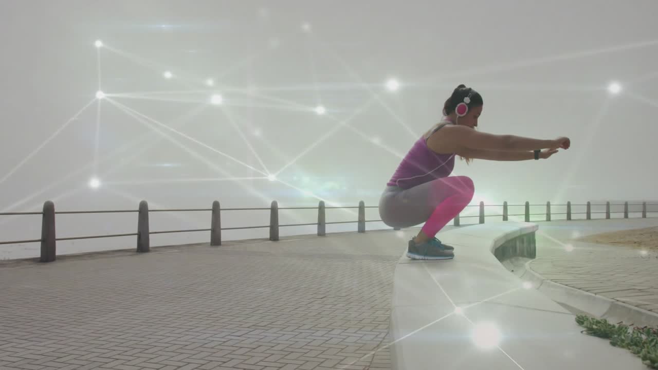 Woman leaning forward and jumping onto curved wall during seaside fitness routine with headphones