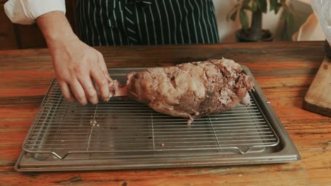 pulling lamb leg out of boiling packed bag for grilling