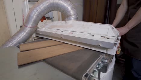 crop luthier flattening wooden planks on planer in workroom