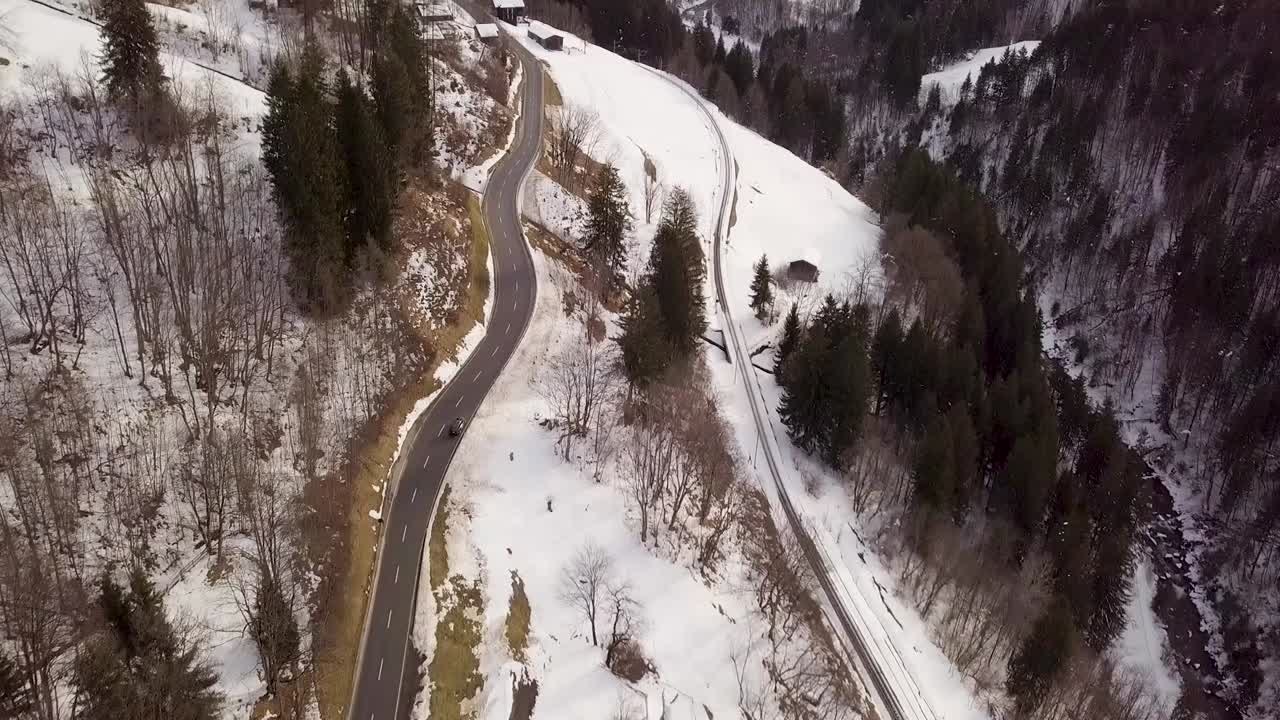 A black car drives into a snowy valley