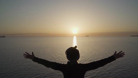 a young girl show victory sign on the top of the hill against the stunning view and sun