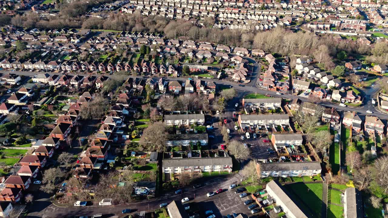 Dronebillede i fugleperspektiv af Sholing, en region i Southampton, England. En smuk forstad med røde huse, haver, befærdede veje med trafik og biler under en smuk vintersolnedgang.