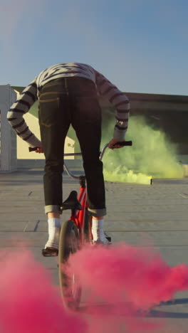 bmx rider on a rooftop jumping and using smoke grenades