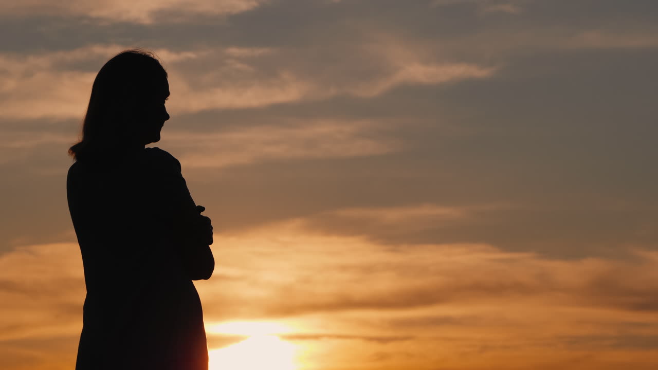 silueta de una mujer joven sola al atardecer mirando a lo lejos