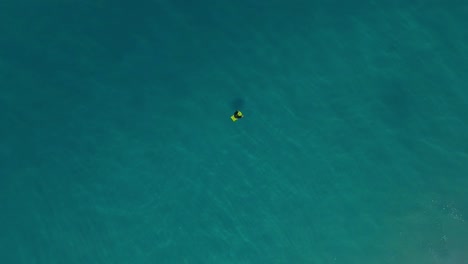 bodyboarder alone in ocean waiting on waves, top down drone view