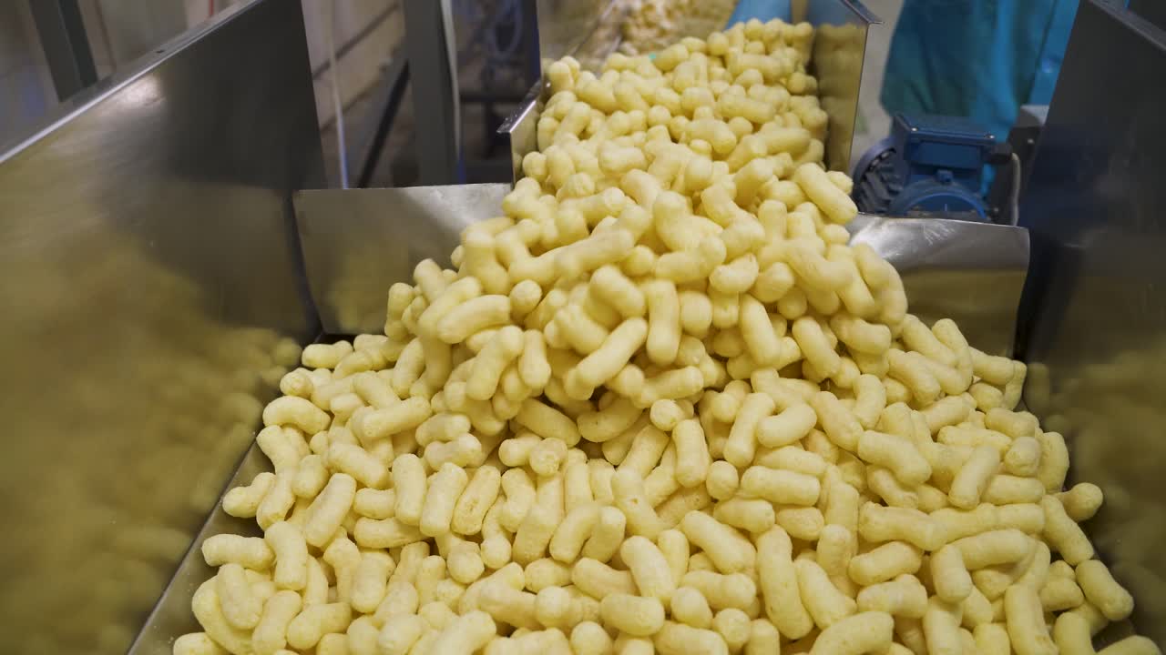 Cheese corn sticks on a conveyor belt. Industrial production of snacks in a factory