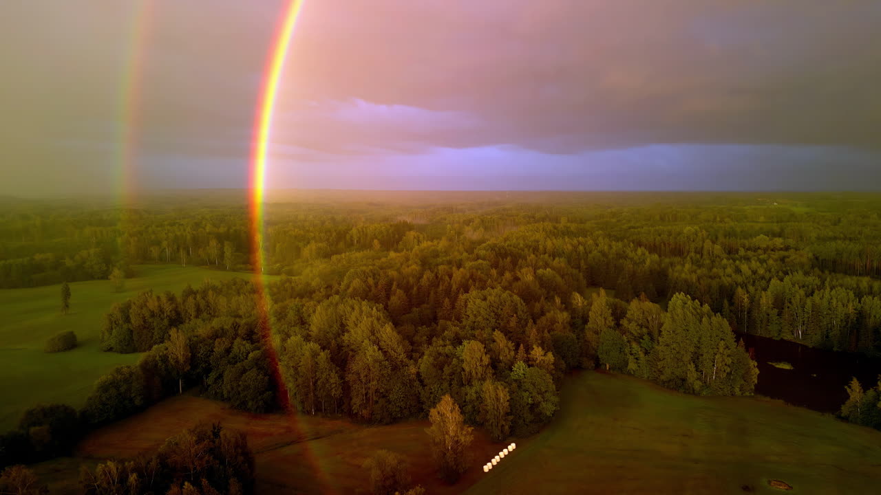 una antena de avión no tripulado bajando sobre un arco iris de tierras de cultivo boscosas