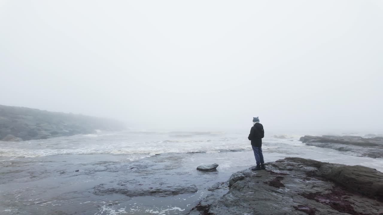 niño de pie en las rocas en un paisaje costero