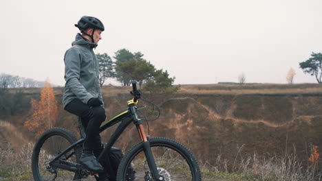 hombre atleta poniéndose una mochila y montando una bicicleta de montaña en la colina