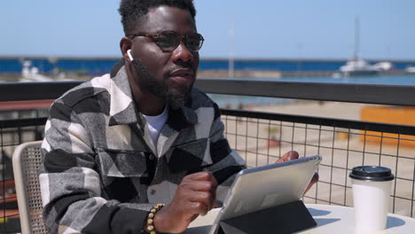 man using tablet outdoors at a cafe