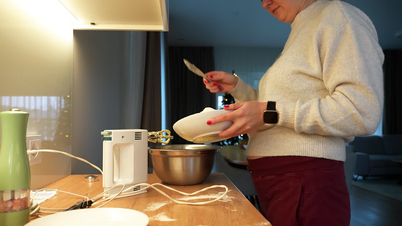 A woman preparing a dish in a modern kitchen, using a mixer and ingredients. The cozy setting is warmly lit, creating a homely atmosphere. Perfect for culinary and lifestyle themes