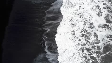 white waves washing upon reynisfjara black sand beach in iceland